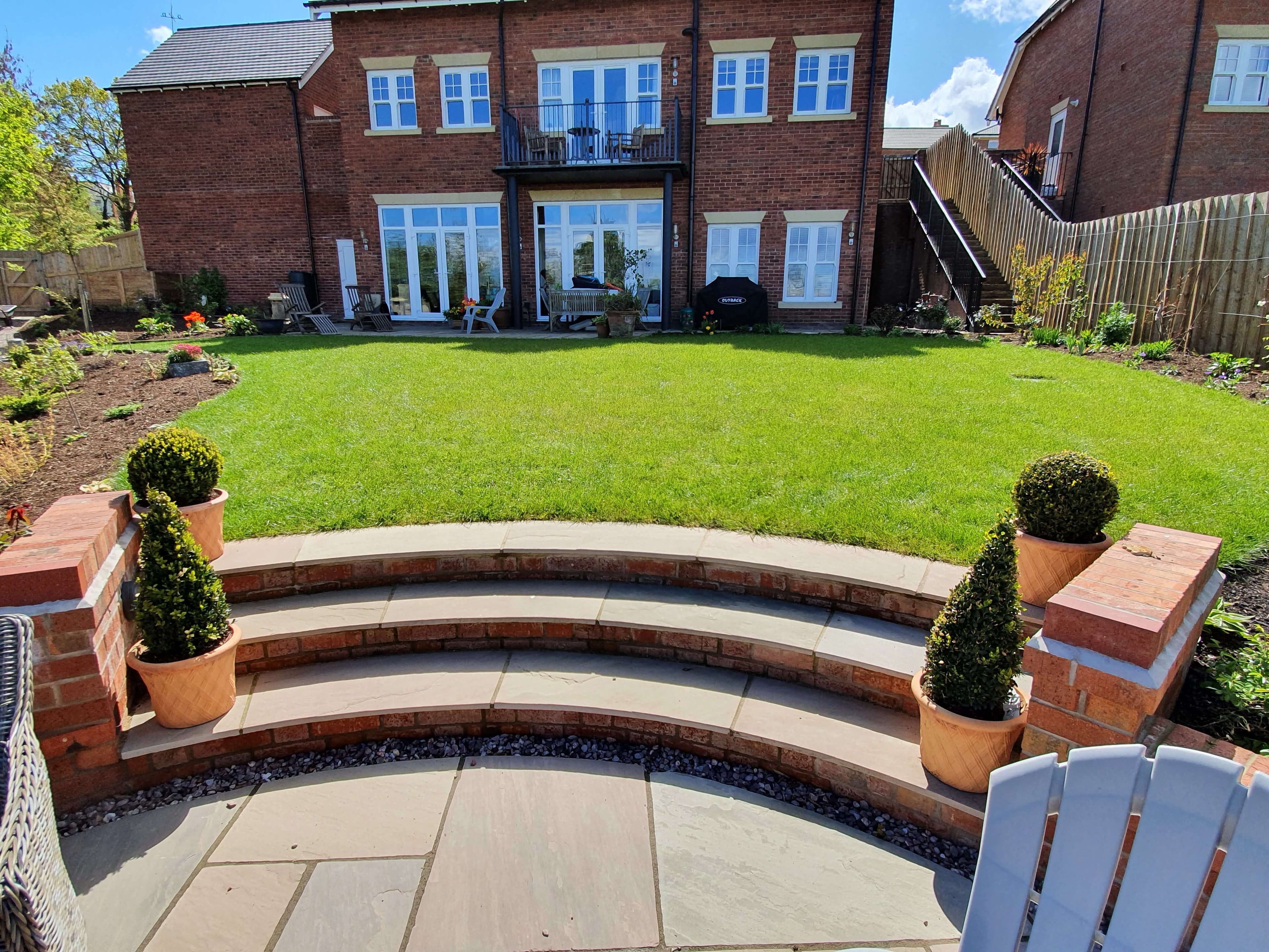 Curved patio steps with topiary planters