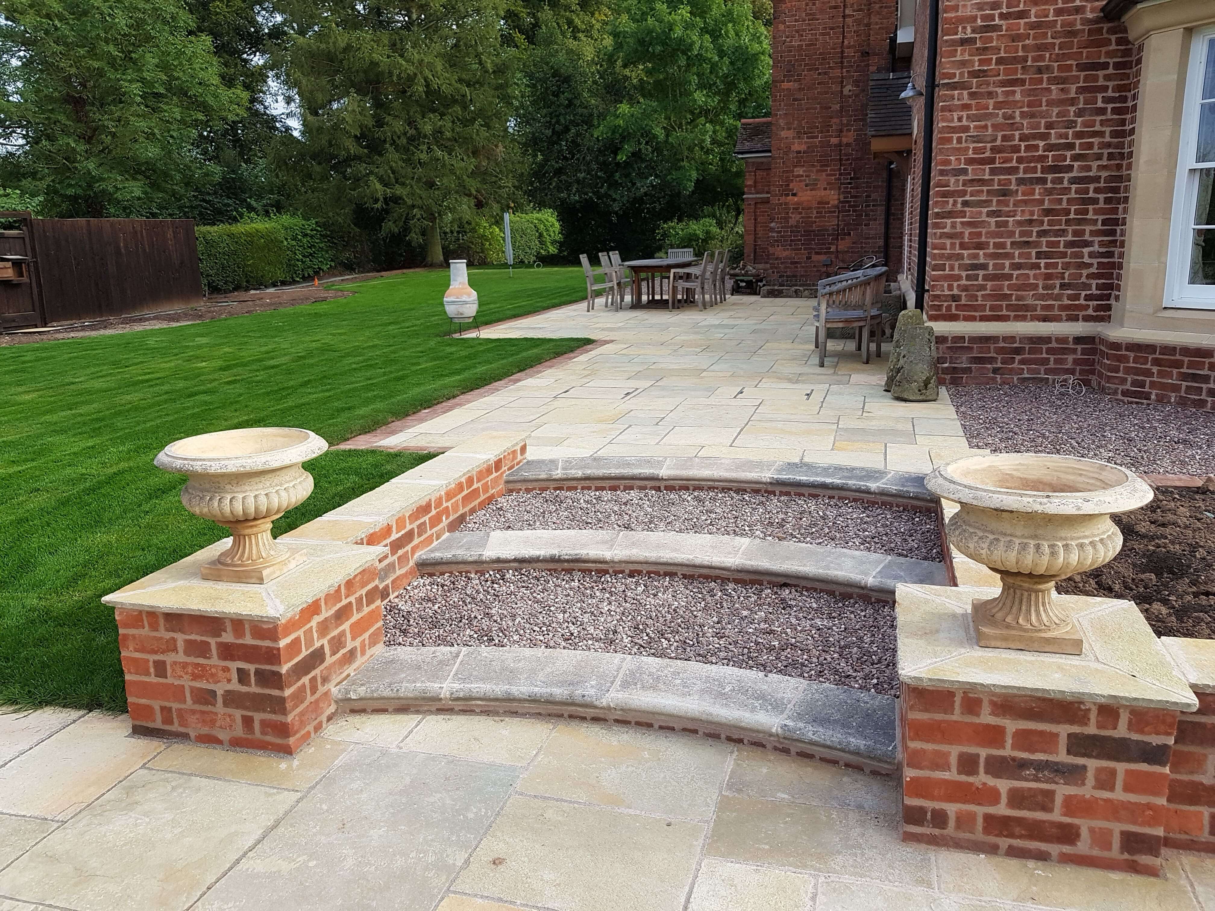 Elegant patio with curved stone steps and lawn